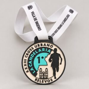 Medalla impresa en 3D del XXXIII Cross Urbano La Candelaria de Ingenio, en negro, crema y turquesa, con la iglesia de La Candelaria, un corredor y cinta blanca impresa